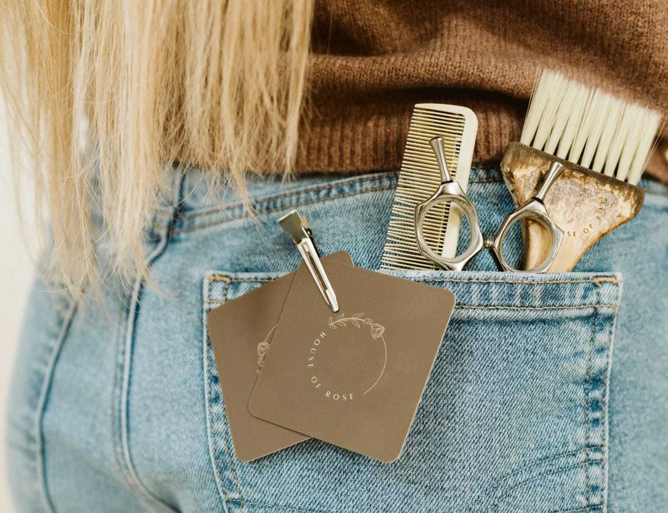 Hair styling tools peeking from back pocket of jeans, including comb and scissors.